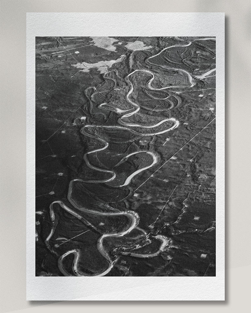 Framed presentation of a winding Canadian landscape photographed from the air